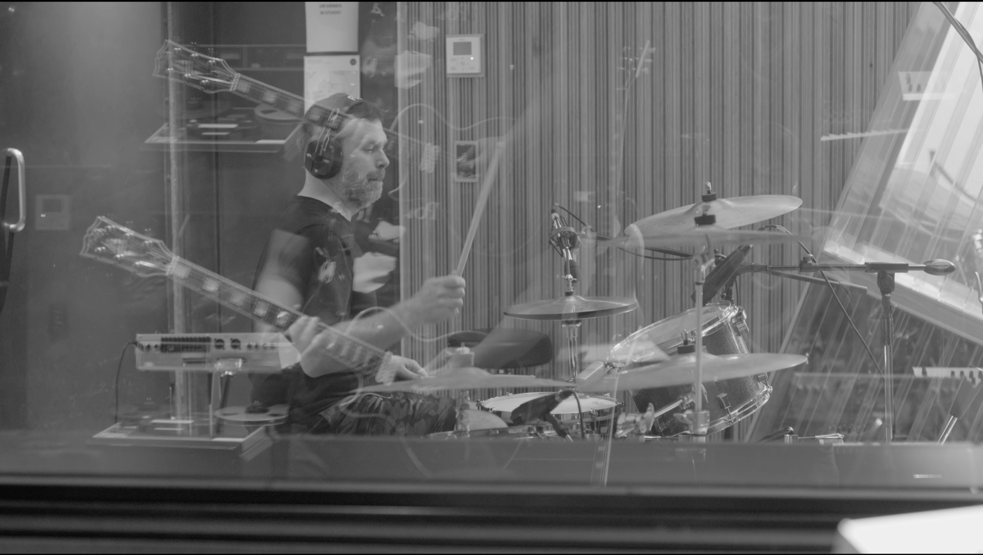 Drummer seen through the studio glass